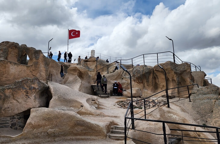 Uçhisar Kalesi’nin zirvesine çıkan ziyaretçiler ve Türk bayrağının dalgalandığı tepe noktası